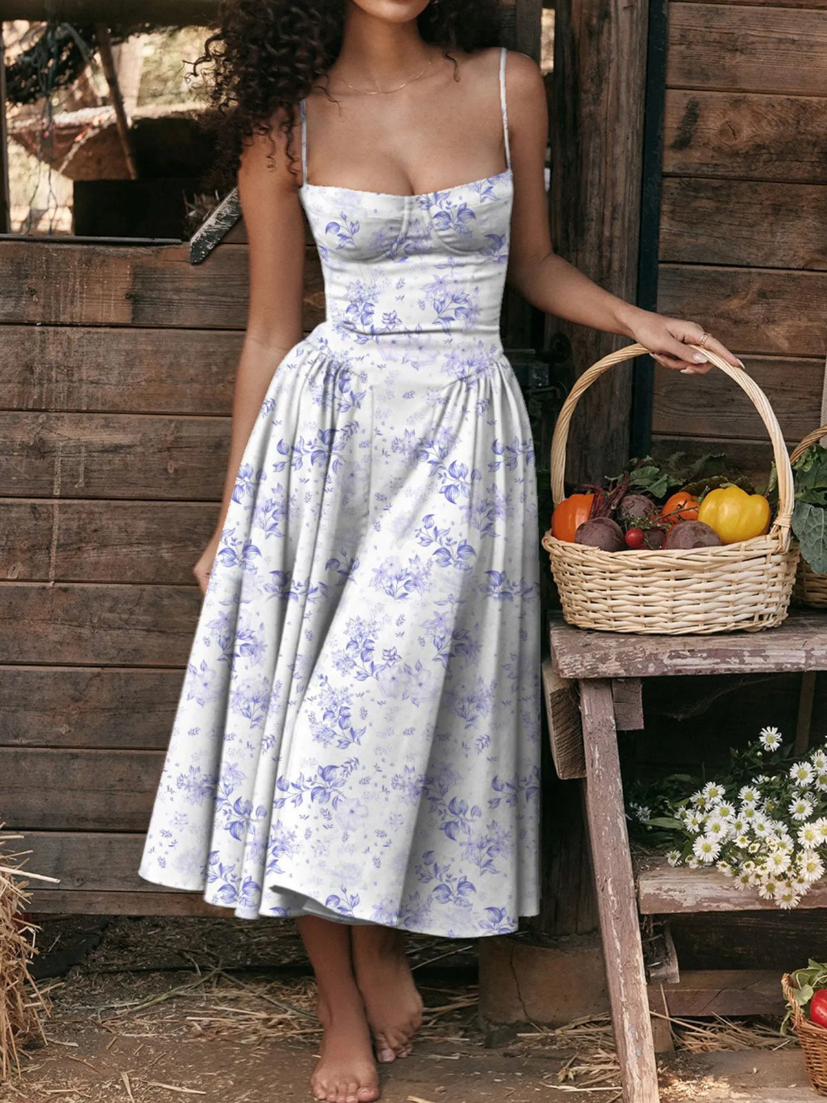 Model wearing a ruched sweetheart neck cami dress with floral design, holding a basket of vegetables.