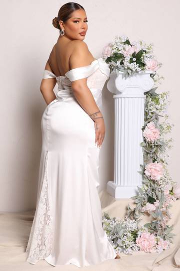 a woman in a white dress standing next to a flower arch