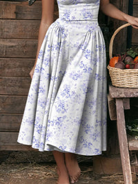 Ruched sweetheart neck cami dress with floral print and flowy skirt, styled outdoors with a basket of fruits.