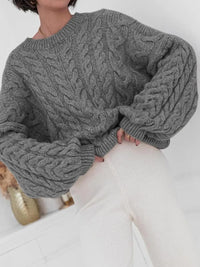 Cozy cable knit long sleeve sweater in grey paired with light pants, showcasing textured knit design and relaxed fit.
