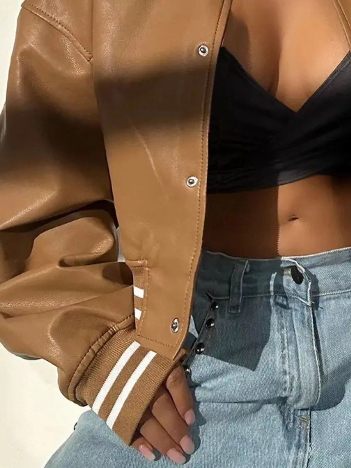 Stylish brown snap down long sleeve jacket paired with a black top and light denim jeans.