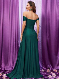 a woman in a green dress standing in front of a purple curtain