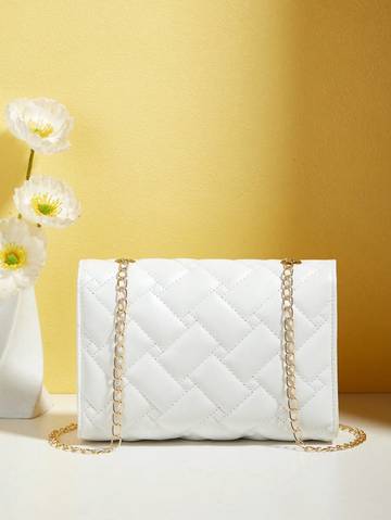 a white purse sitting next to a vase with flowers