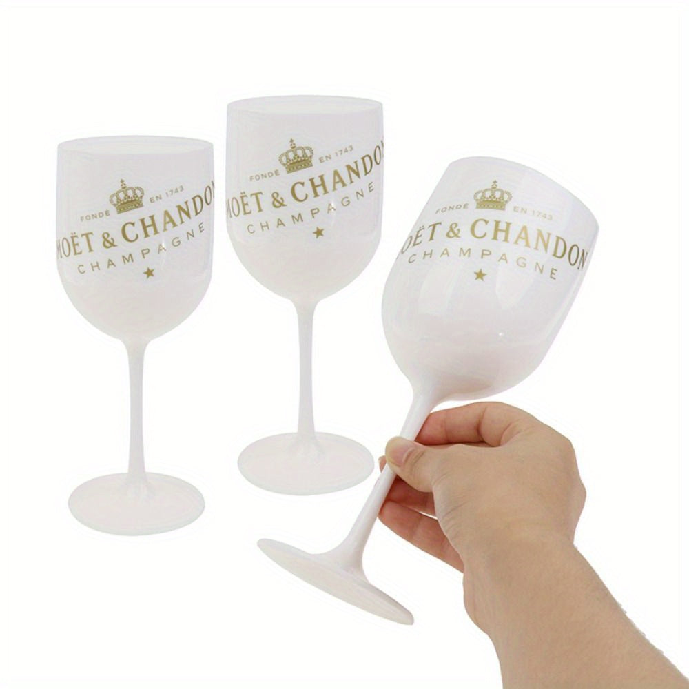 a hand holding three wine glasses with gold lettering
