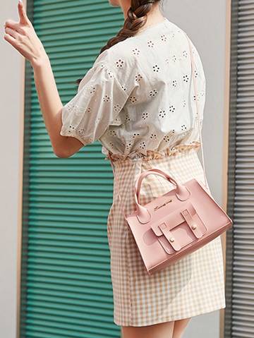 a woman carrying a pink handbag while standing next to a building