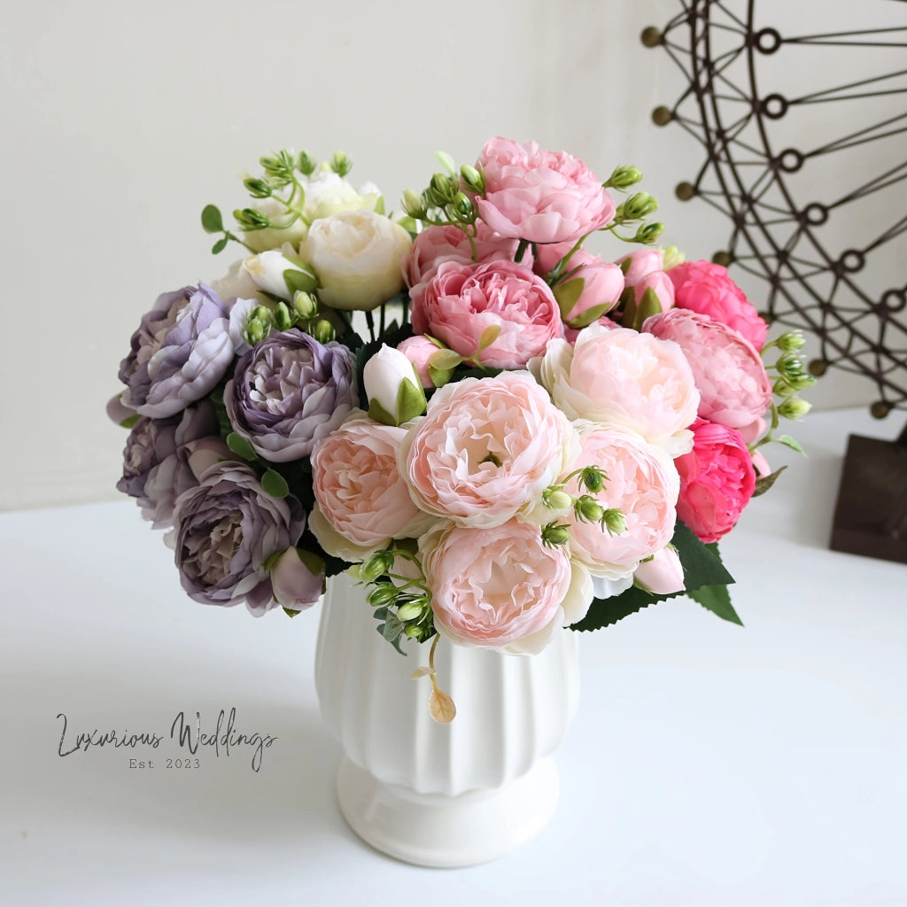 a white vase filled with lots of pink and purple flowers