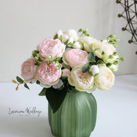 a green vase filled with pink and white flowers