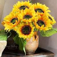 a vase filled with yellow sunflowers on top of a table