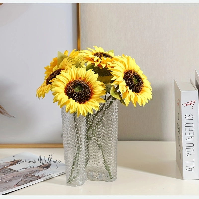 a vase filled with yellow sunflowers next to a book