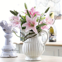 a white vase filled with pink flowers on top of a table
