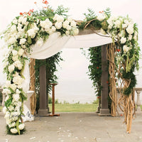 a wedding arch decorated with white flowers and greenery