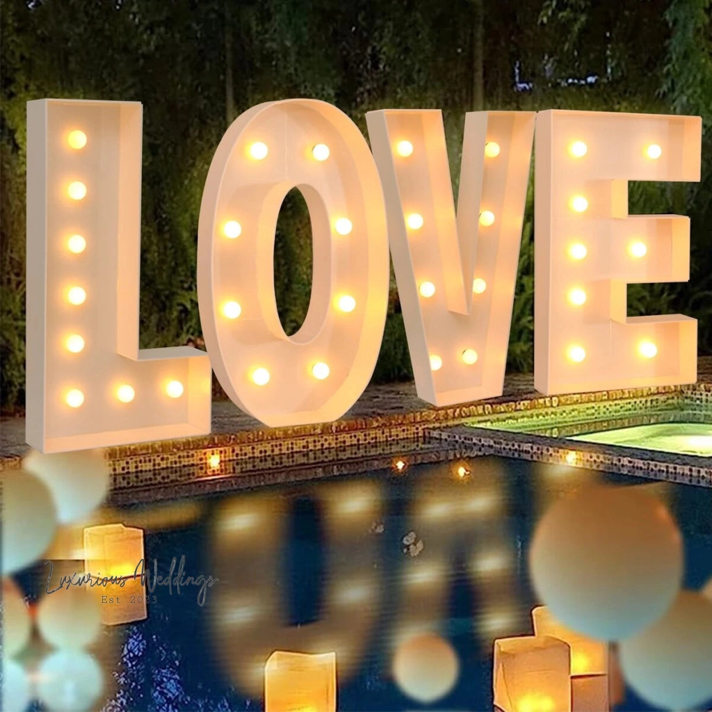 a lighted love sign sitting next to a pool