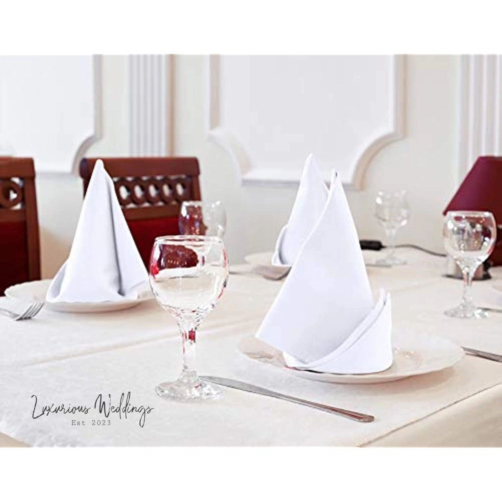 a table set for a formal dinner with napkins and wine glasses