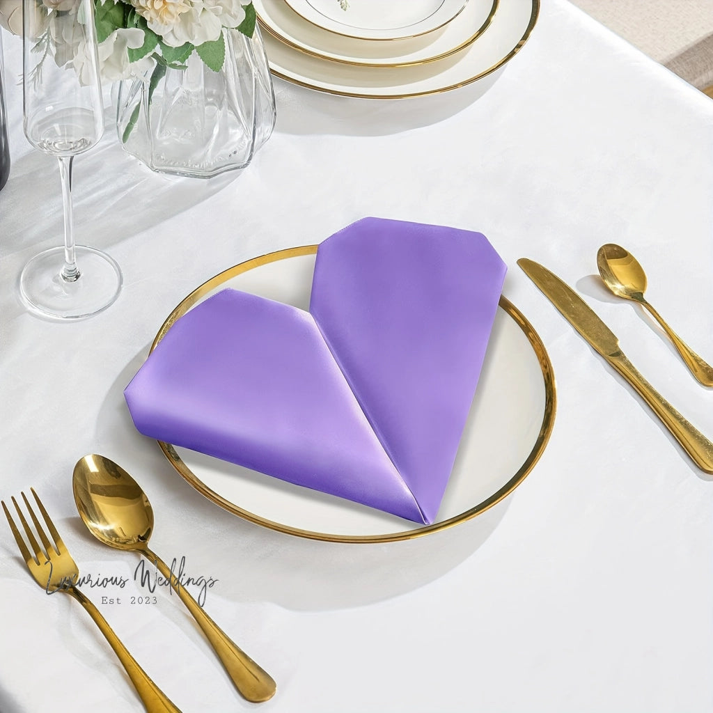 a place setting with purple napkins and gold place settings