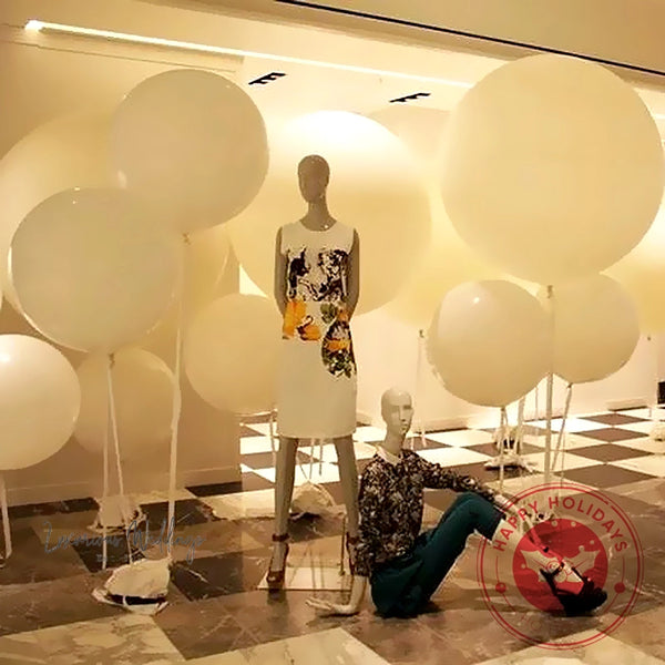 a man sitting on the ground next to a bunch of balloons