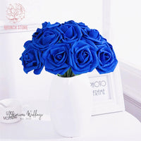 a white vase filled with blue roses on top of a table