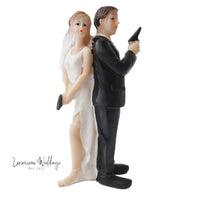 a figurine of a bride and groom holding a cell phone