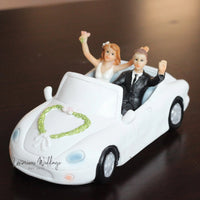 a wedding cake topper of a bride and groom in a car