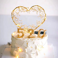 a white cake with gold decorations and a heart shaped cake topper