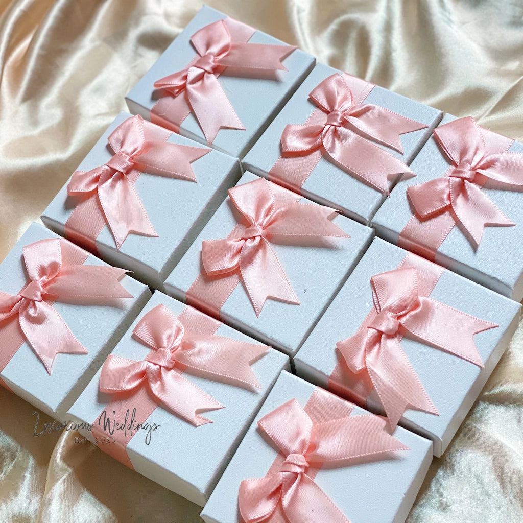 a bunch of small boxes with pink bows on them
