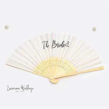 a white and gold fan with the word the bride written on it