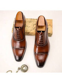 a pair of brown shoes sitting on top of a wooden block