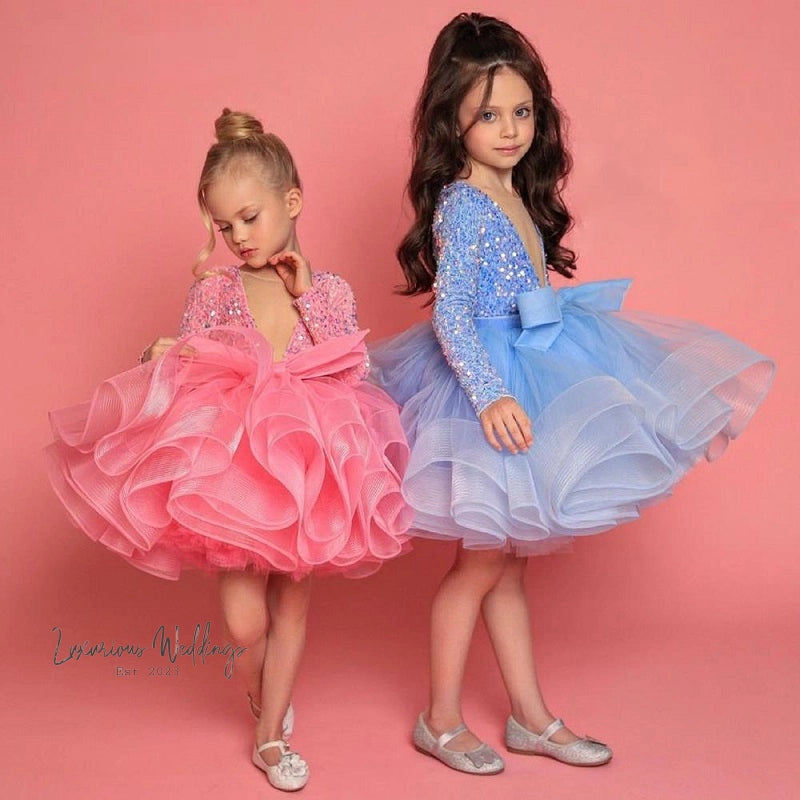 two little girls in dresses standing next to each other