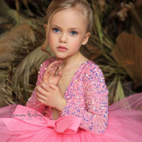 a little girl wearing a pink dress and a pink bow