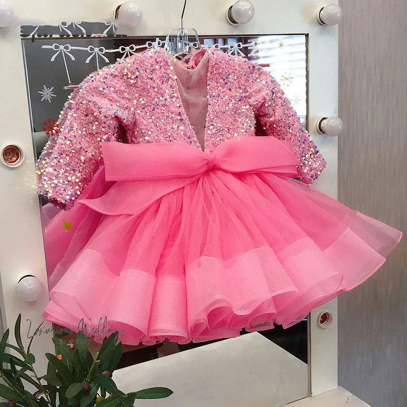 a little girl's pink dress hanging on a mirror