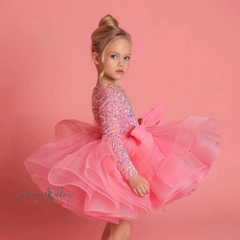 a little girl in a pink dress posing for a picture