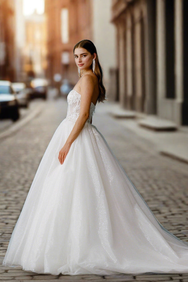 a woman in a wedding dress standing on a brick street
