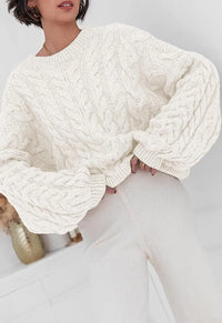 Model wearing a cozy cable knit long sleeve sweater in cream, styled with soft, relaxed-fit pants.