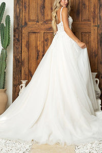 Bride in elegant A-line wedding dress with lace appliqués and chapel train standing by wooden doors with cactus in background