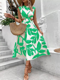 Cutout printed sleeveless dress with green leaf pattern, perfect for summer styling, paired with a straw bag and sandals.