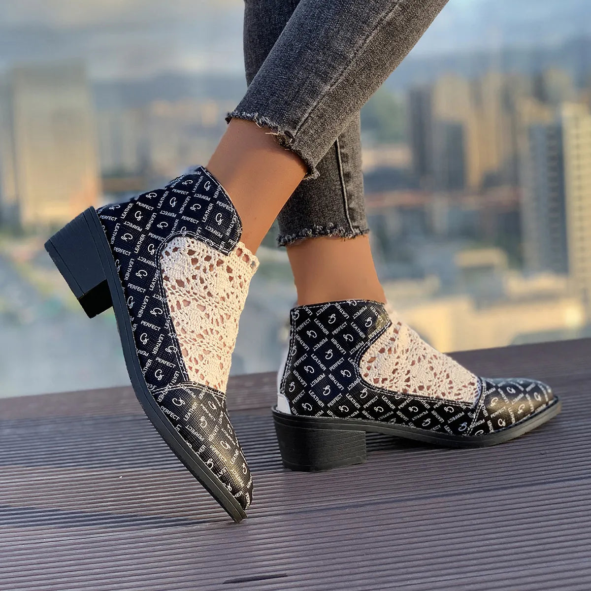 Stylish printed point toe block heel boots in black and cream, featuring mesh panels and low heels, perfect for modern outfits.