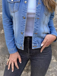 Plus size button front long sleeve denim jacket styled with high-waisted black jeans.