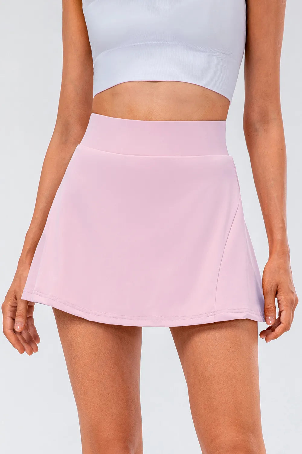 High waist pleated active skirt in soft pink, highlighting stretchy fabric and flattering A-line cut.