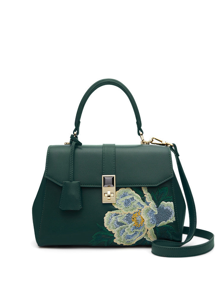 a green handbag with a flower on it