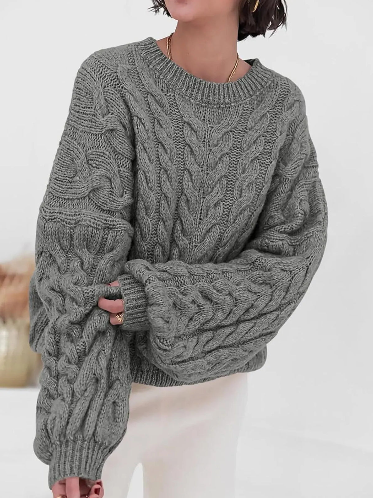 Cozy gray cable knit long sleeve sweater featuring a relaxed fit and oversized sleeves.