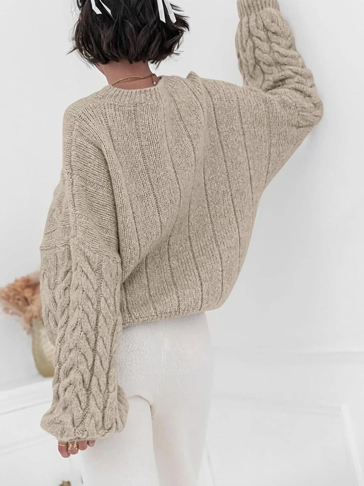 Cozy cable knit long sleeve sweater in tan, showcasing a relaxed fit and textured pattern from the back.