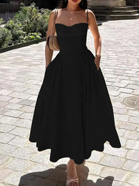 Model wearing a black ruched sweetheart neck cami dress with pockets, styled in a sunny outdoor setting.