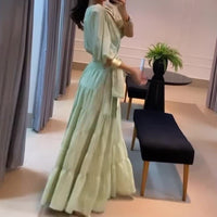 a woman in a long green dress taking a picture of herself