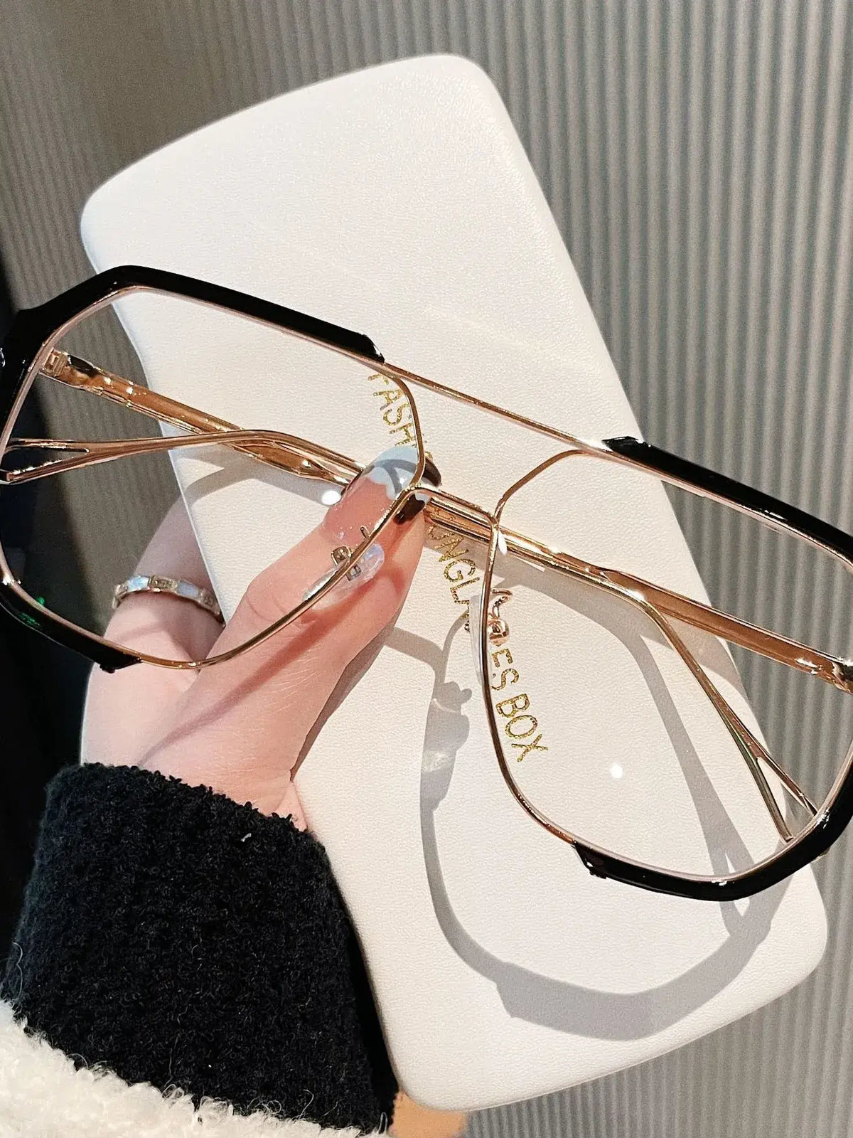 Oversized UV protection sunglasses with alloy frame held above a stylish glasses case, perfect for luxurious weddings.