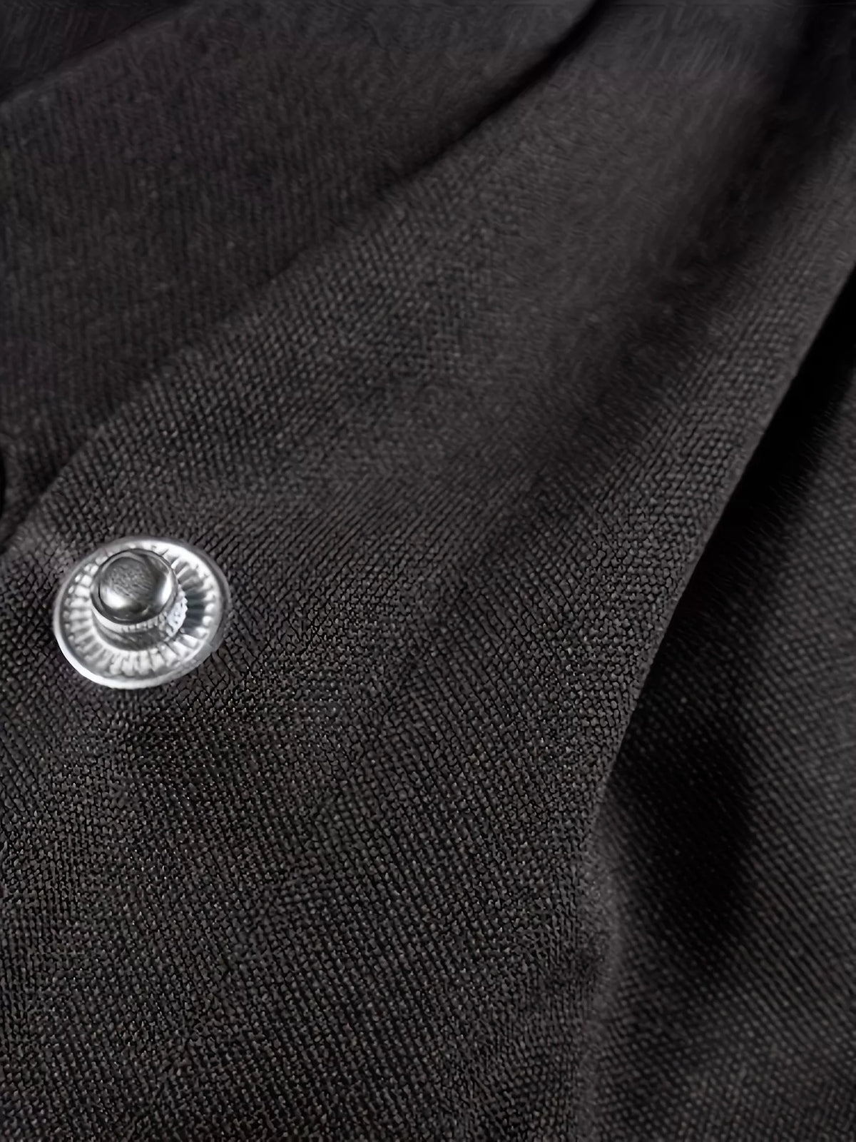 Close-up of a black fabric showing a button detail, part of the Snap Down Long Sleeve Jacket.