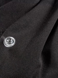 Close-up of a black fabric showing a button detail, part of the Snap Down Long Sleeve Jacket.