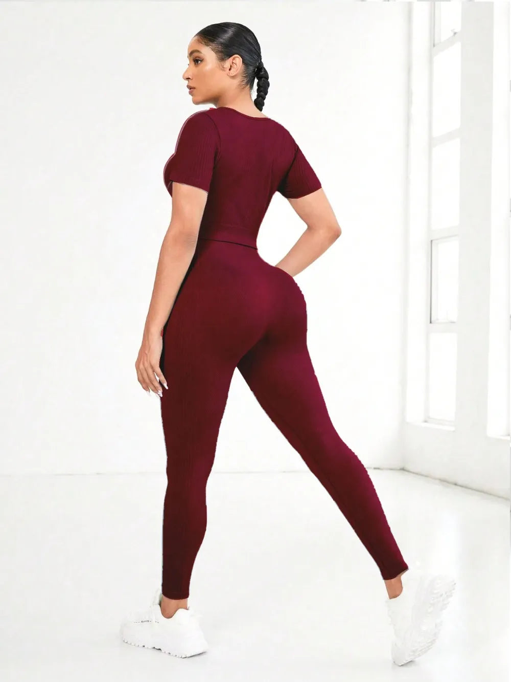 Model wearing a burgundy round neck short sleeve top and leggings active set, showcasing a fitted silhouette.