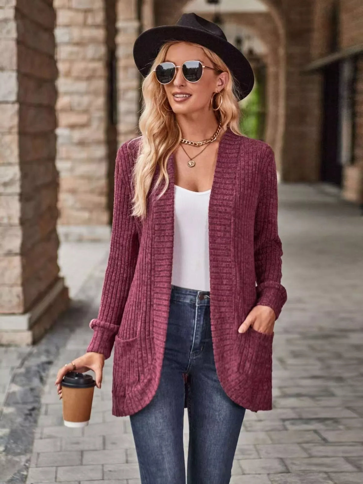 Woman wearing a maroon open front ribbed knit cardigan with pockets, sunglasses, and a coffee cup.