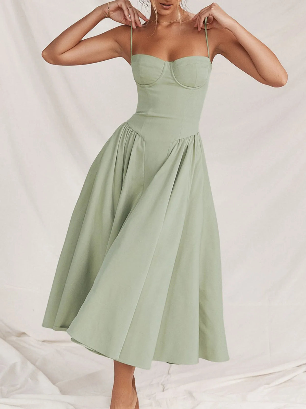 Ruched sweetheart neck cami dress in light green, featuring a flowing skirt and adjustable straps.