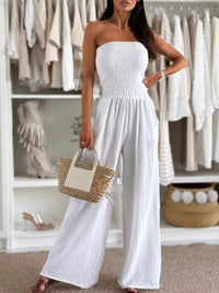 White smocked tube wide-leg jumpsuit modeled with a stylish handbag, ideal for formal wear & accessories NZ.