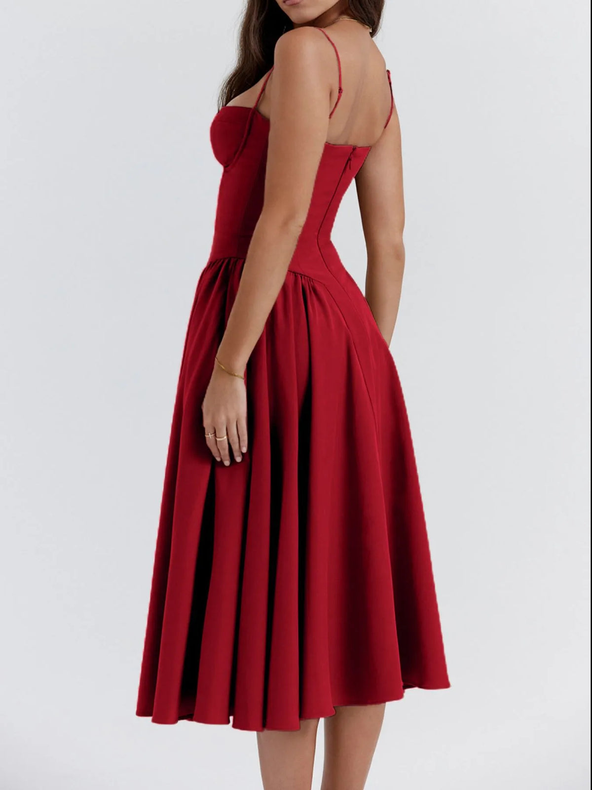Model wearing a ruched sweetheart neck cami dress in red, showcasing the back and flowy pleated skirt.